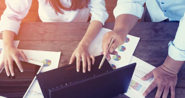 man and women at desk looking over business finance charts