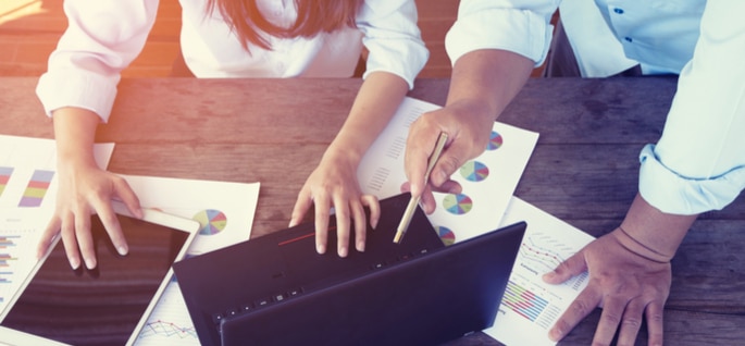 man and women at desk looking over business finance charts
